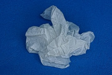 one piece of crumpled white sheet of paper lies on a blue table