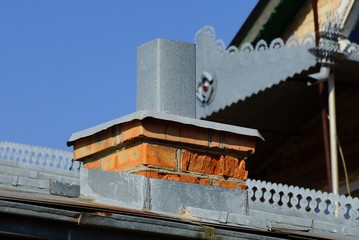 Fototapeta na wymiar a small chimney of brown brick gray metal on the roof