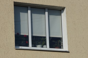 large window with white shutters on the gray wall of the building