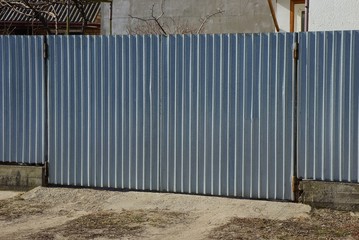 gray metal gate and part of the fence on the street