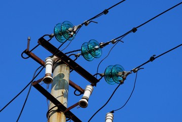 part of a concrete pillar with wires against a blue sky