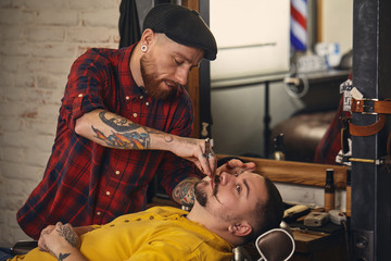 Client during beard shaving in barber shop