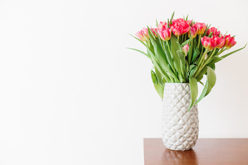 A bouquet of pink red white peony tulips in a gray modern vase on wooden tabel