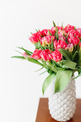 A bouquet of pink red white peony tulips in a gray modern vase on wooden tabel