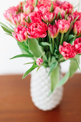 A bouquet of pink red white peony tulips in a gray modern vase on wooden tabel