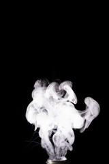 Fototapeta na wymiar Splash glicerine on vape spiral. White thick fog with visible tracers. Vape culture and no smoking. Smoke rising up. Underexposed stock photo isolated on black background