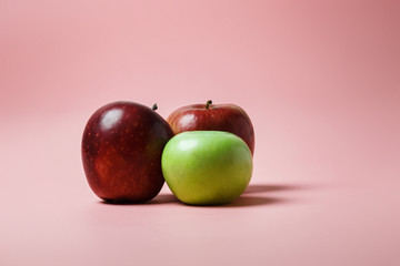 Beautiful ripe juicy red and green apples from their own garden on a pink background. Good snack at night and snack after sport