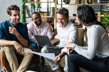 Business team using laptop and discussing documents in loft office