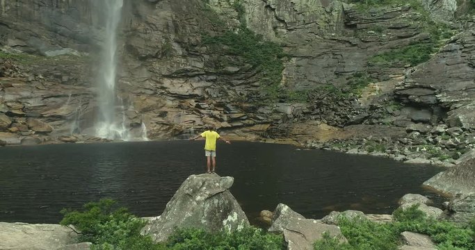 Man on top of the stone contemplating giant waterfall