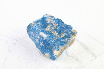Natural mineral - rough Lazurite, Lapis Lazuli from Pamir, Tajikistan on white cement background.