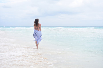 Fototapeta na wymiar Back view - woman walking along seashore