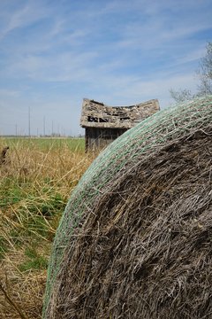 Abandoned house behind a hay bale
