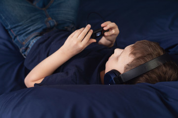 boy listening to music in headphones Lying in bed