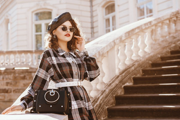 Outdoor fashion portrait of young beautiful fashionable lady wearing trendy  long checkered dress,...