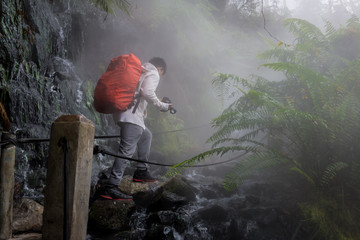 A man is crossing the path of a hot spring stream in the Gunung Gede Pangrango forest