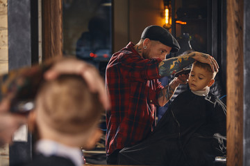 Caucasian boy getting haircut in barbershop indoor