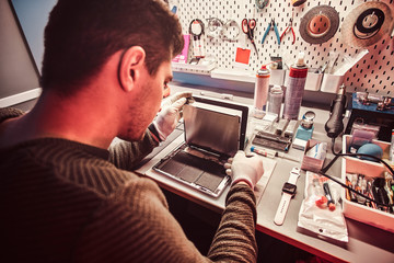 The technician repairs a broken tablet computer in a modern repair shop