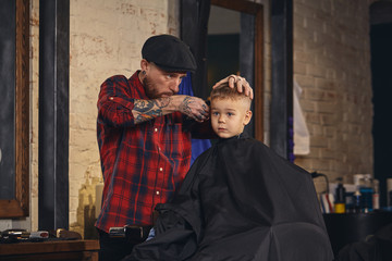 Caucasian boy getting haircut in barbershop indoor