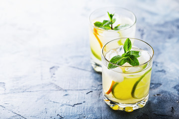 Invigorating tonic with lemon, lime and mint in transparent glasses on the table with copy space