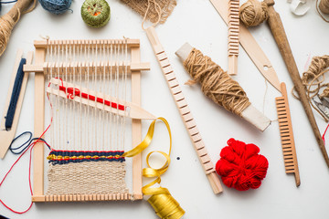 Tools for weaving and thread lie on a white table