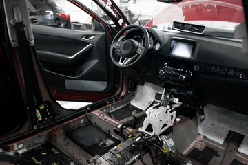 Car repair and service station. Automobile disassembly. Warranty. Vehicle interior. Wires stick out from the dashboard. Wheel and airbag.