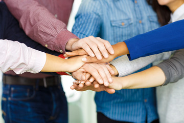 Mixed race cheerful business team piling their hands one on top of another