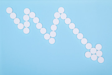 Medical pills in the form of graphics. White round pills on blue background. Concept reducing the dosage of medication.Empty place to insert text copy