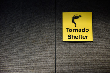 Bright yellow Tornado, or Twister shelter sign, designating a safe room area. 