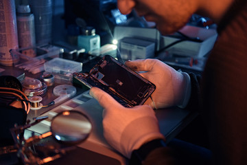 The technician carefully examines the integrity of the internal elements of the smartphone in a modern repair shop