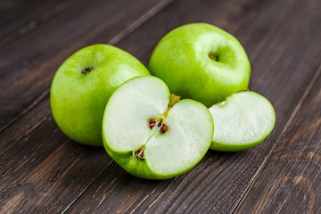 Ripe green apples and apple slices on old wooden background.