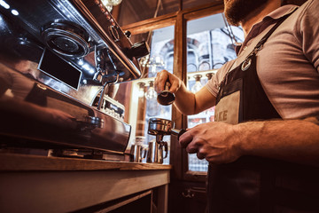 Low angle photo of a barista holding a portafilter, working in the coffee shop or restaurant