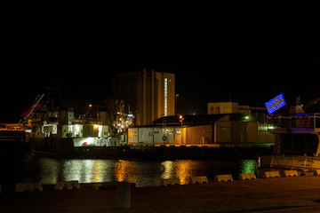 Fototapeta na wymiar Industrial harbor in the evening with a ship and silo
