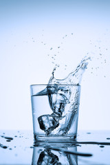 Frozen splashes of clean, spring water, in a glass with ice, on a white background.