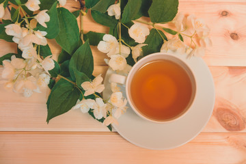 Cup of green tea and white jasmine flowers on wooden table. Selective focus.