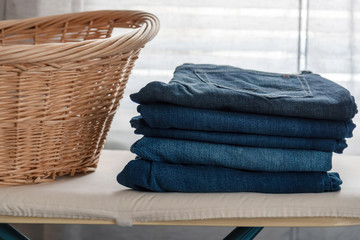 Stack of men's jeans folded on the ironing board