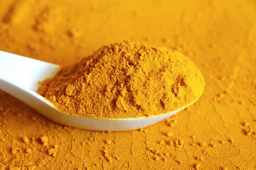 turmeric or curcumin longa powder in spoon isolated on turmeric powder spice background