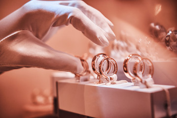 Hand in gloves takes to exclusive rings on the showcase of a luxury jewelry store