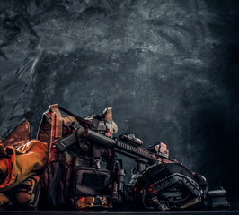 Obraz premium Military uniform and equipment. Body armor, gun, assault rifle, helmet, night vision goggles. Studio photo against a dark textured wall