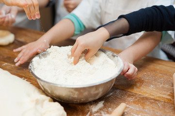 Children's hands take the flour from the plate