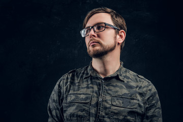 Portrait of a bearded guy in glasses looking right in the studio on a black background