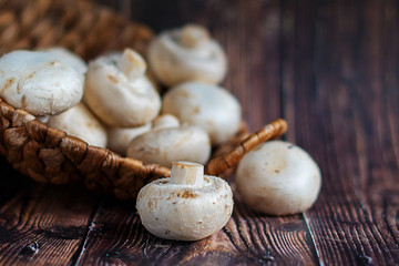 Fresh mushrooms in a basket on a wooden background. Stock photo.