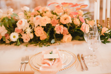 Coziness and style. Modern event design. Table setting at wedding reception. Floral compositions with name card on vintage plate on decorated table.