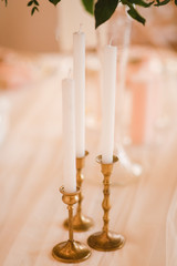 Coziness and style. Modern event design. Table setting at wedding reception. Floral compositions with beautiful flowers and greenery, candles, laying and plates on decorated table.