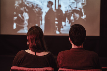 Back view of a young couple on a date watching a retro movie in the cinema
