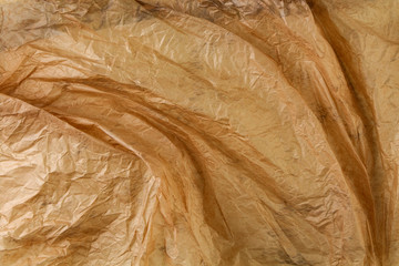 Brown thin crumpled paper closeup, texture background.