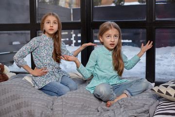 The cute little girl is snitching at her sister, pointing at her with her finger