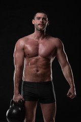 Fototapeta na wymiar Handsome young man trains with dumbbells with water splashes on his face and chest in Studio shot