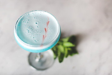 Bright Blue glass of cocktail martini on a bar with mint