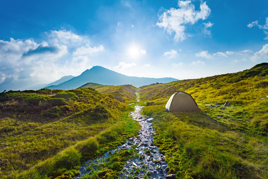 Perfect campig spot landscape with stream, mountains and tent