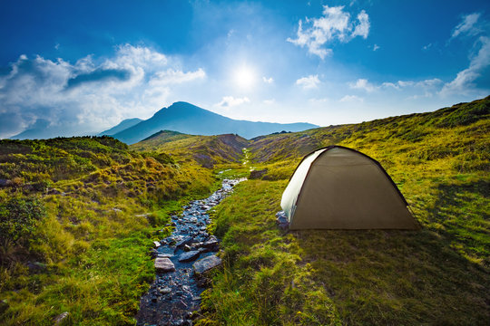 Perfect campig spot landscape with stream, mountains and tent